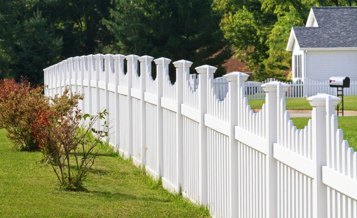 White fence with a few bushes next to it