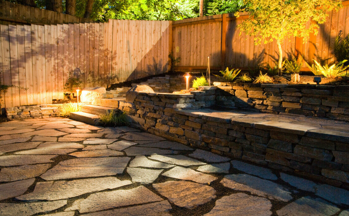Stone-paved backyard lit up with solar lights