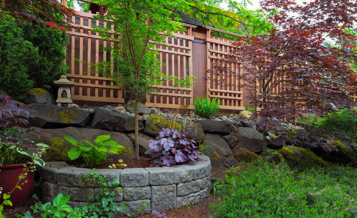 Backyard featuring rock and stone hardscaping, as well as a wooden fence.